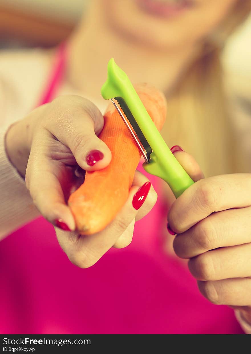 Woman peeling vegetables using food peeler. Cooking female preparing carrot before serving. Woman peeling vegetables using food peeler. Cooking female preparing carrot before serving