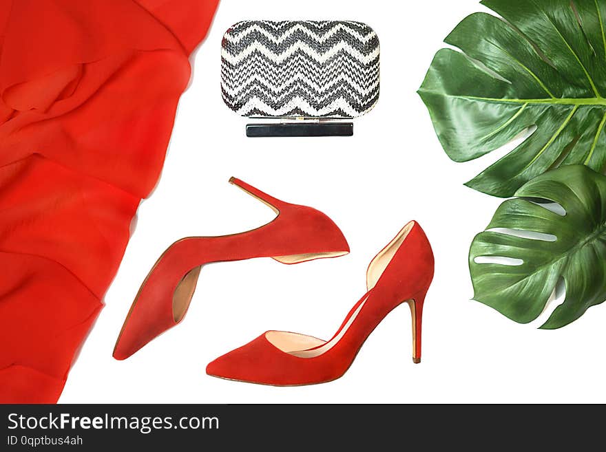 Top view party outfit red shoes accessories clutch tropical monstera leaves on white background, isolated. Party Valentine`s Day Christmas Happy New Year wedding dinner layout. Flat lay, copy space.