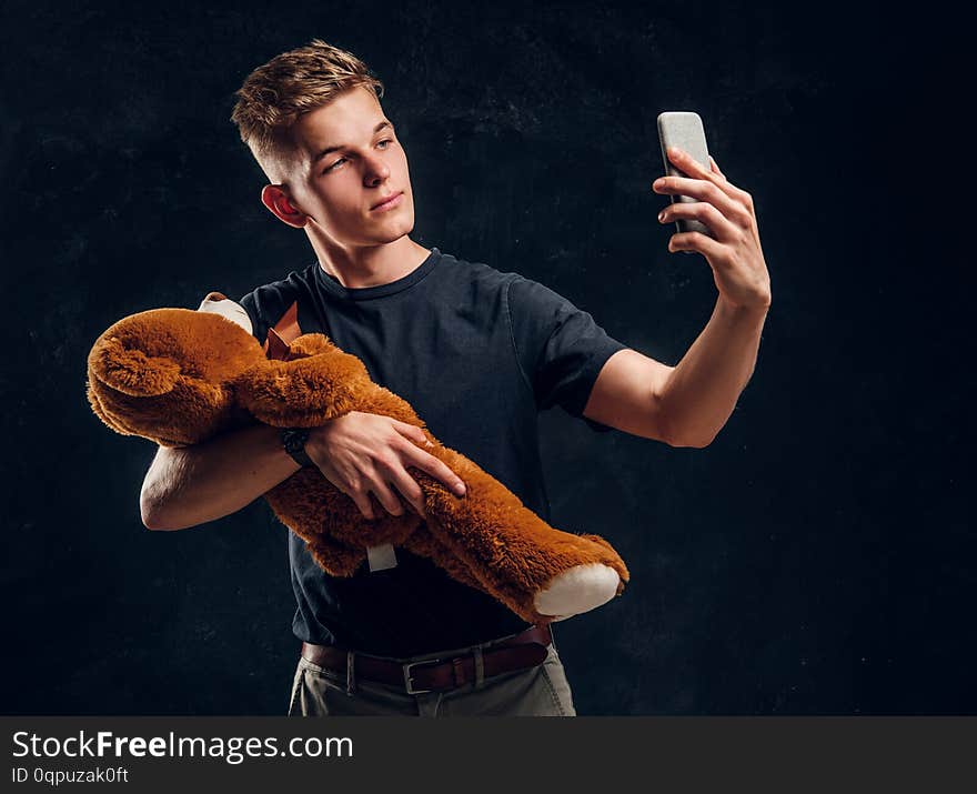 Young attractive man is making selfie with plush toy