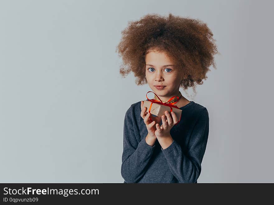 portrait of a smiling cute girl with curly hair and a red gift in her hands. .portrait of a smiling cute girl with curly hair and a red gift in her hands