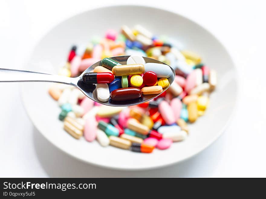 Various types of tablets, capsules and pills on  spoon with colorful medicine background. Top view