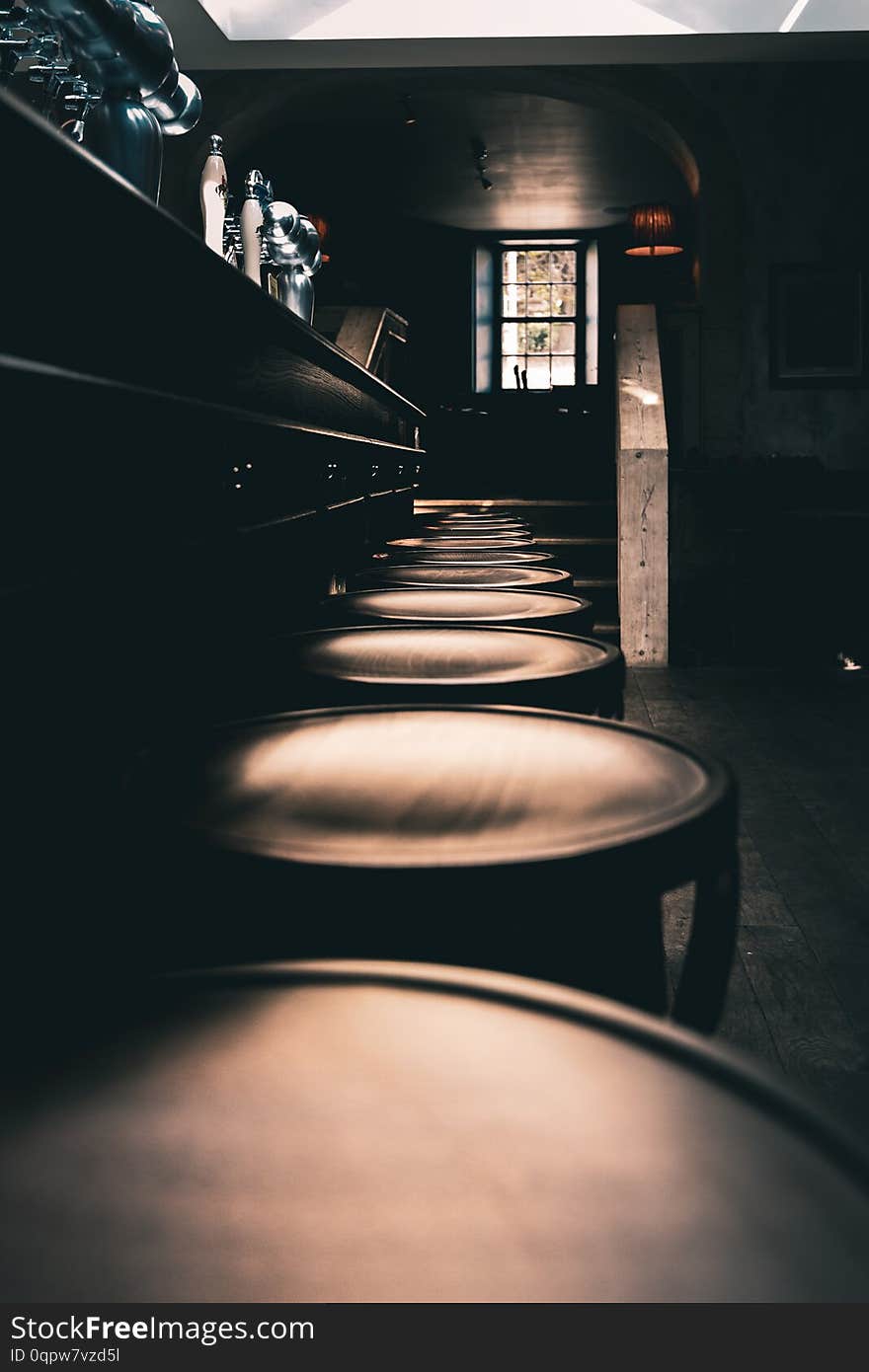 Dramatic shot of wooden stools in a row at the bar of an old English Pub in the North of England.