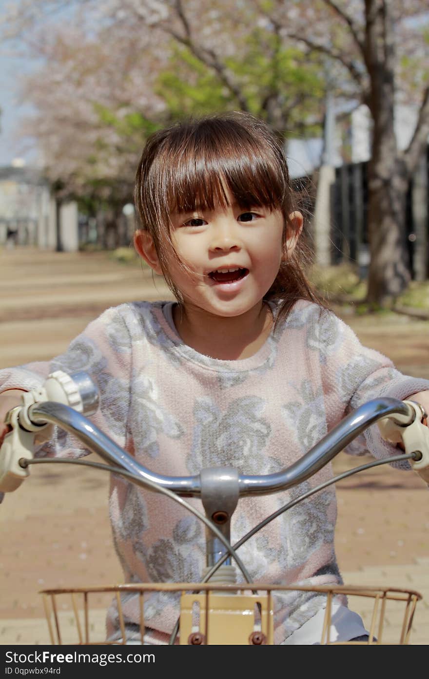 Japanese girl riding on the bicycle under cherry blossoms