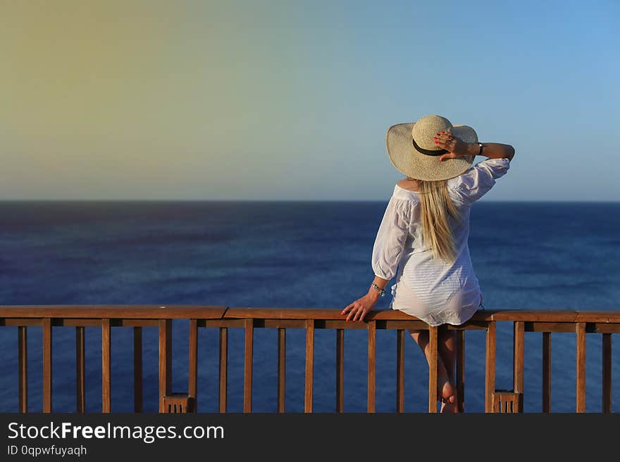 Outdoor summer portrait of young pretty woman looking to the sea, enjoy her freedom and fresh air, wearing stylish hat and clothes.