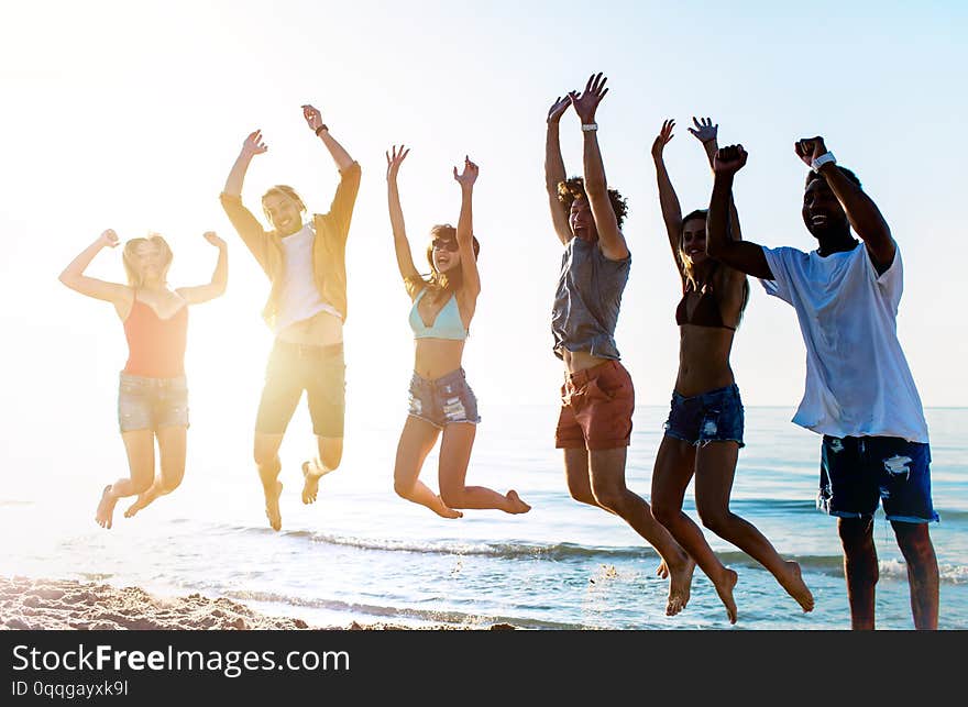 Happy Smiling Friends Jumping At The Beach