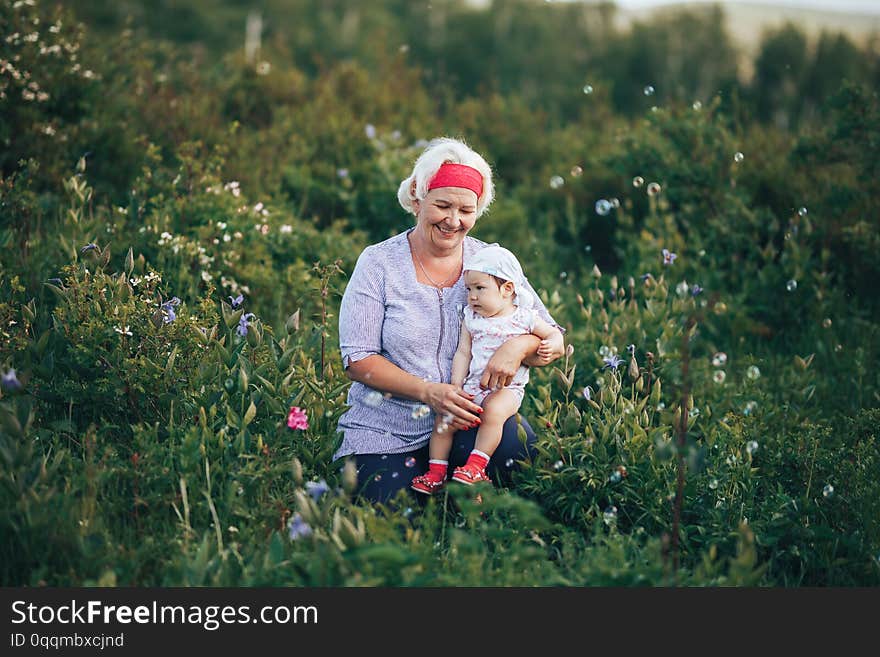 Grandmother Hugging granddaughter In nature in sunny summer day