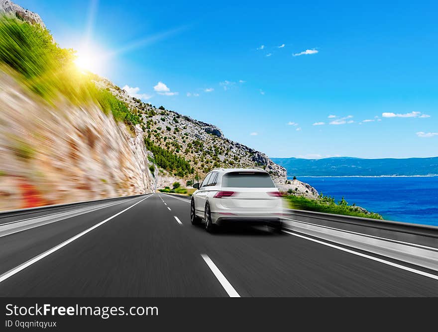 White car rushes along the road to the sea. Motion blur effect.