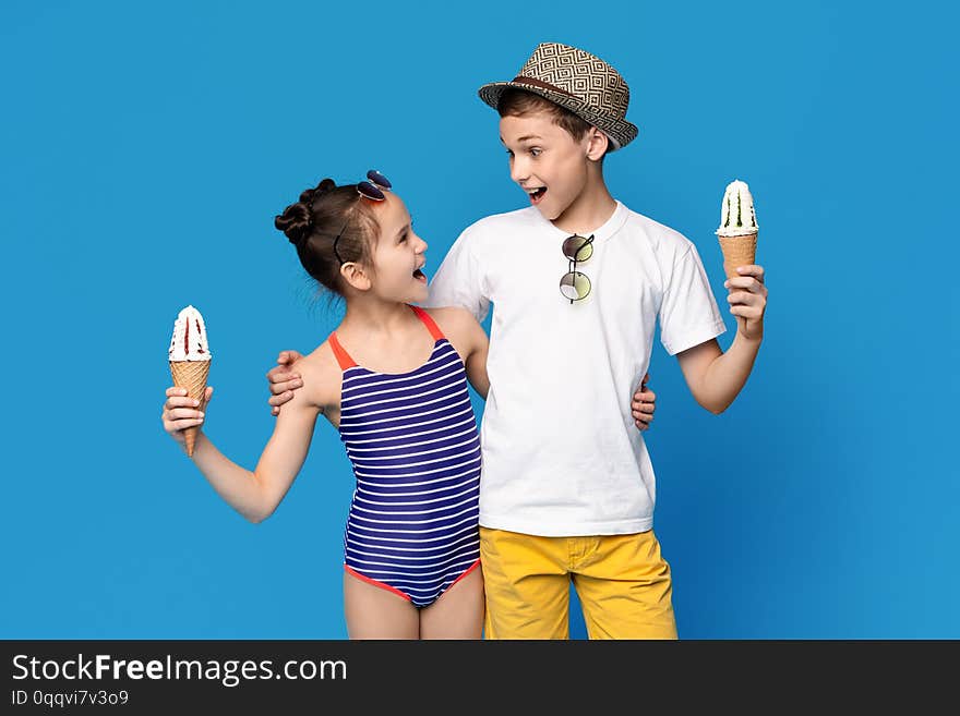 Excited little boy and girl embracing with ice cream cones