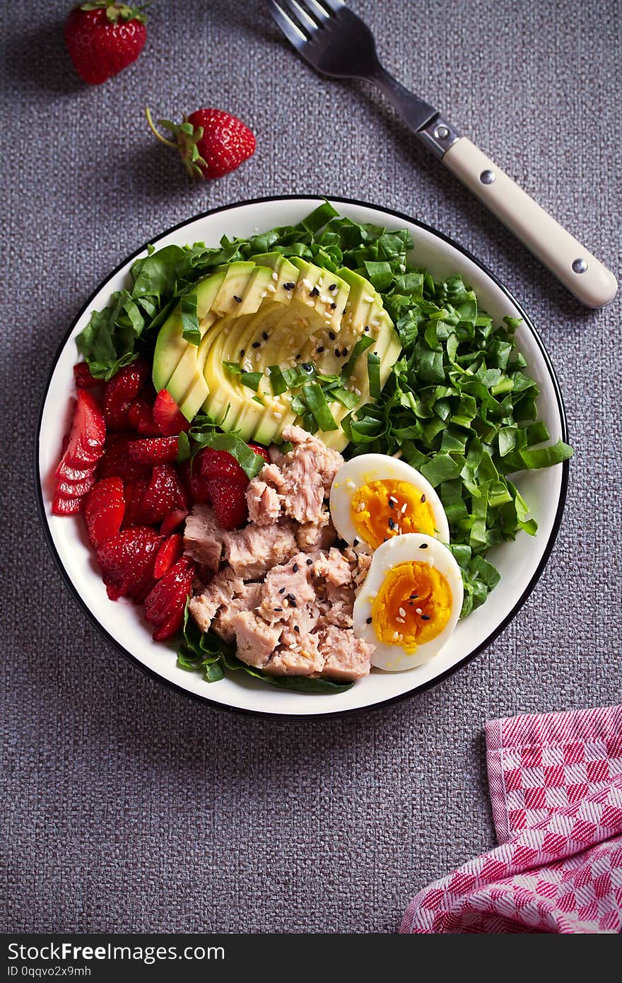 Tuna strawberry avocado egg and spinach salad in bowl - healthy food.