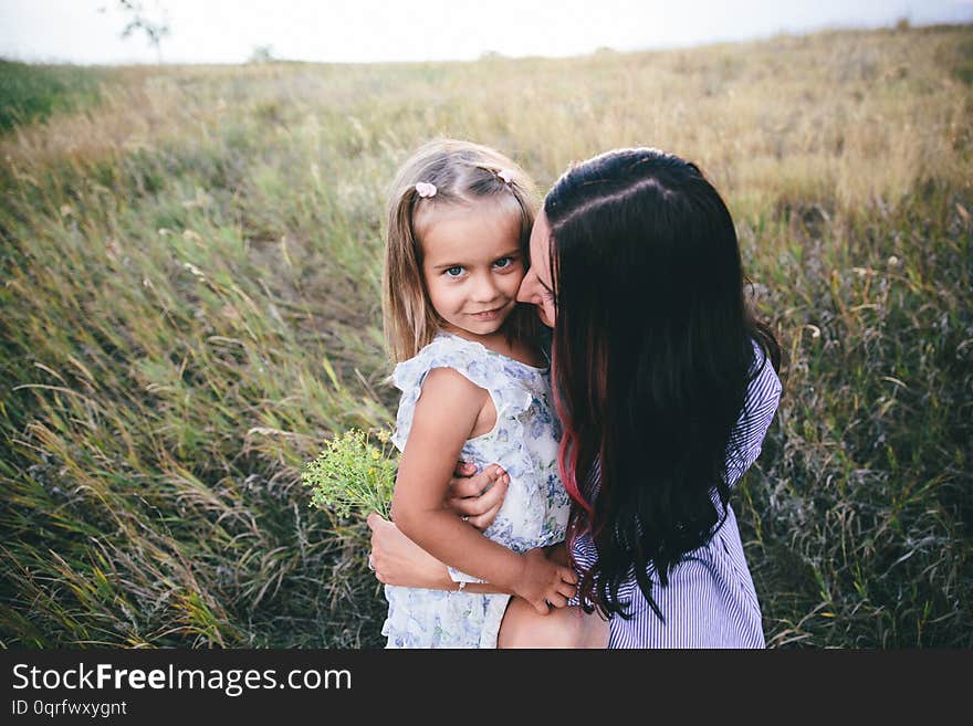 Mother And Daughter Are Relaxing In Wheat Field At Spring Time.