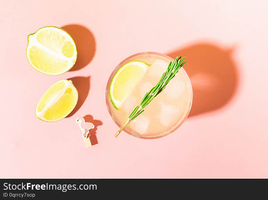 A refreshing drink of lemon and lime lemonade in a transparent glass on a pink pastel background bright sunlight. Summer cocktail or mojito. Top view flat layout. Copy space. Concept minimalism. A refreshing drink of lemon and lime lemonade in a transparent glass on a pink pastel background bright sunlight. Summer cocktail or mojito. Top view flat layout. Copy space. Concept minimalism