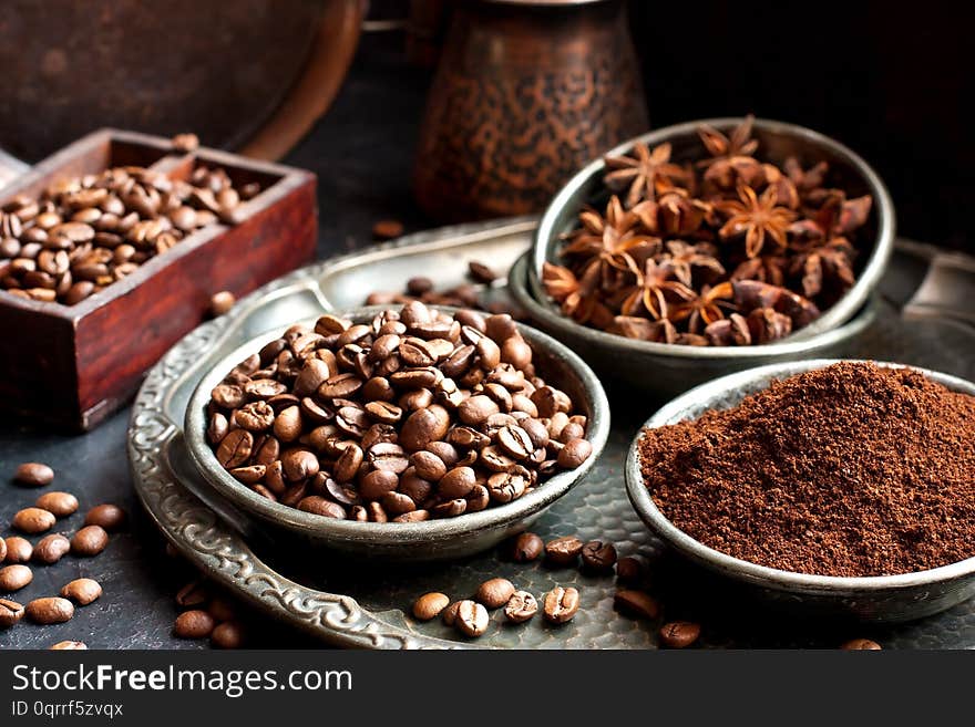 Food  background  with  black roasted coffee beans, ground coffee and anise in dishes, selective  focus with  shallow depth of field. Food  background  with  black roasted coffee beans, ground coffee and anise in dishes, selective  focus with  shallow depth of field