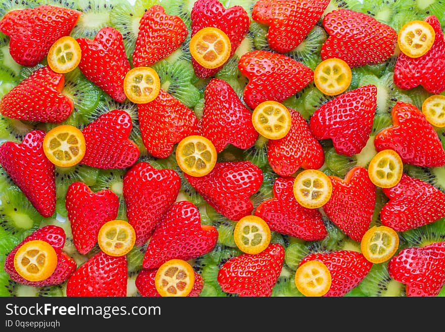 creative concept of sliced kiwi flower shape, strawberry heart shape and kumquat like background