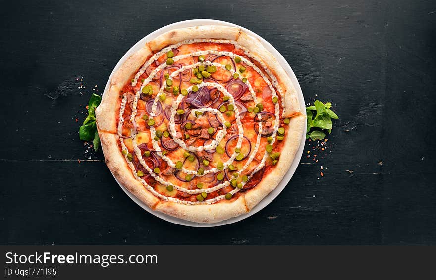 Pizza with onions, sausage and cucumber. On a wooden background. Top view. Free space for your text