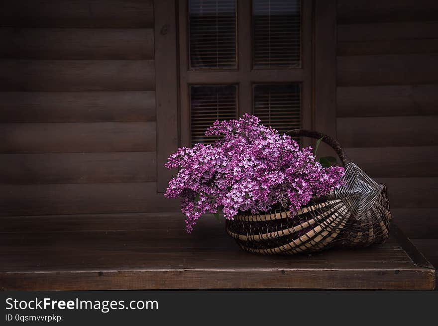 Bouquet of aroma lilacs in a basket on a dark wooden background