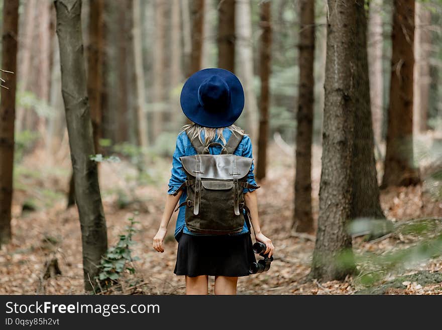 Young woman with binocular and backpack in a forest