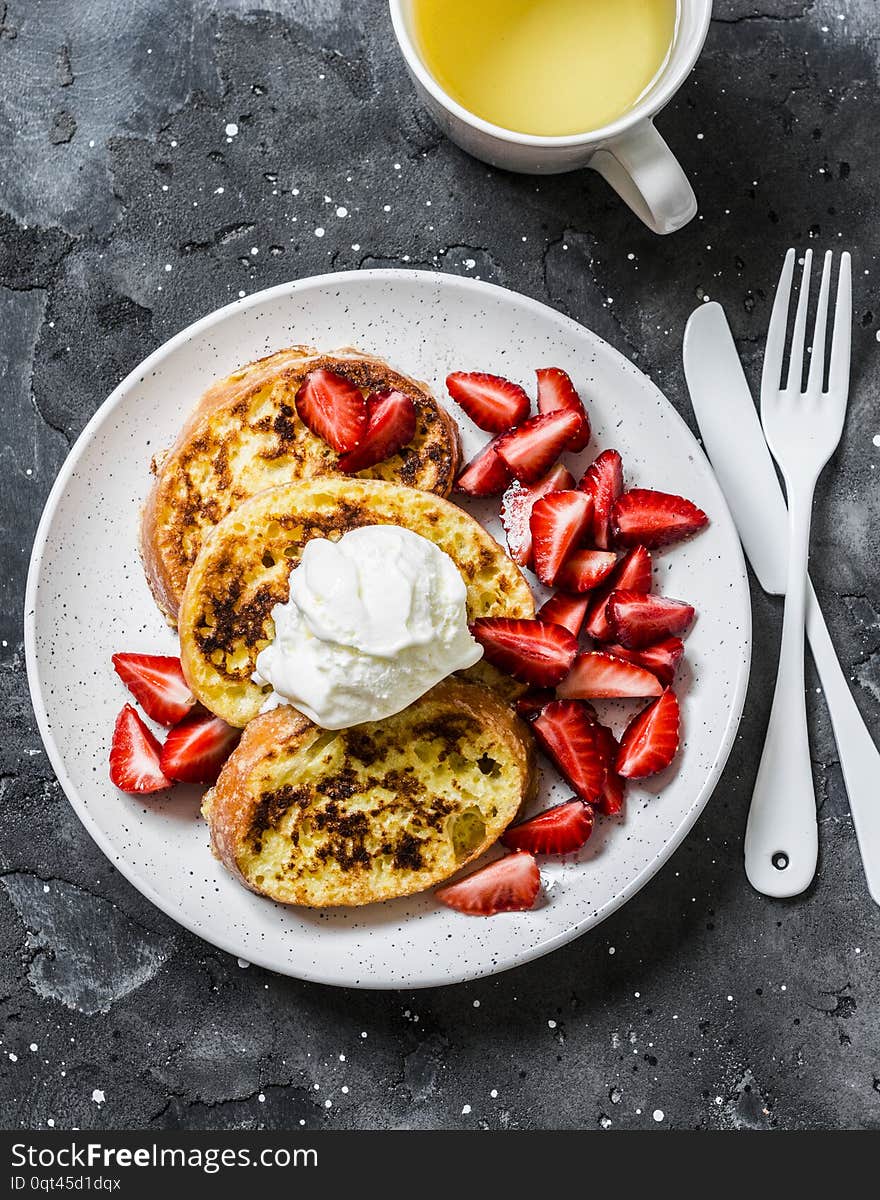 Baked french toast with ice cream and strawberries on a dark background, top view. Delicious breakfast, dessert, snack.Flat lay