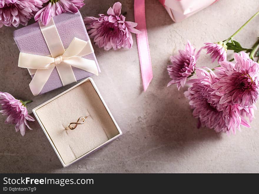 Box with beautiful engagement ring with flowers on table