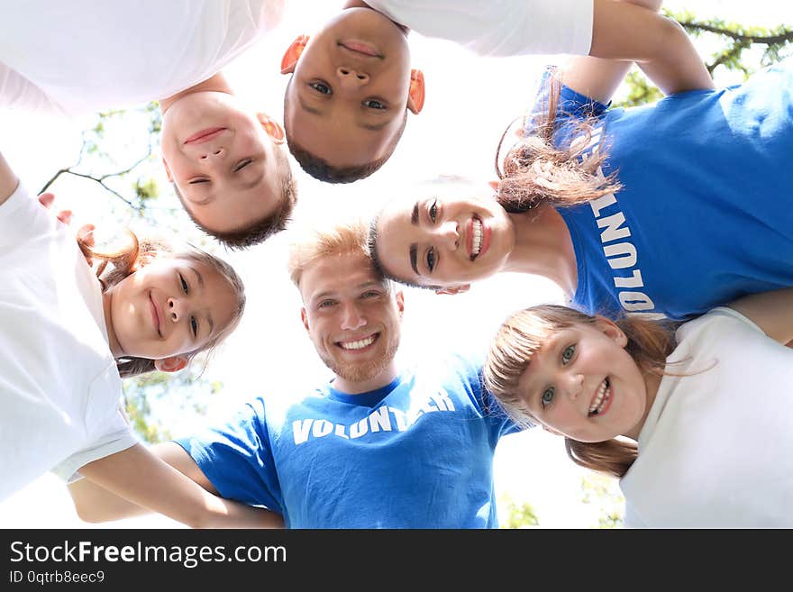 Low angle view of volunteers huddling with kids in park