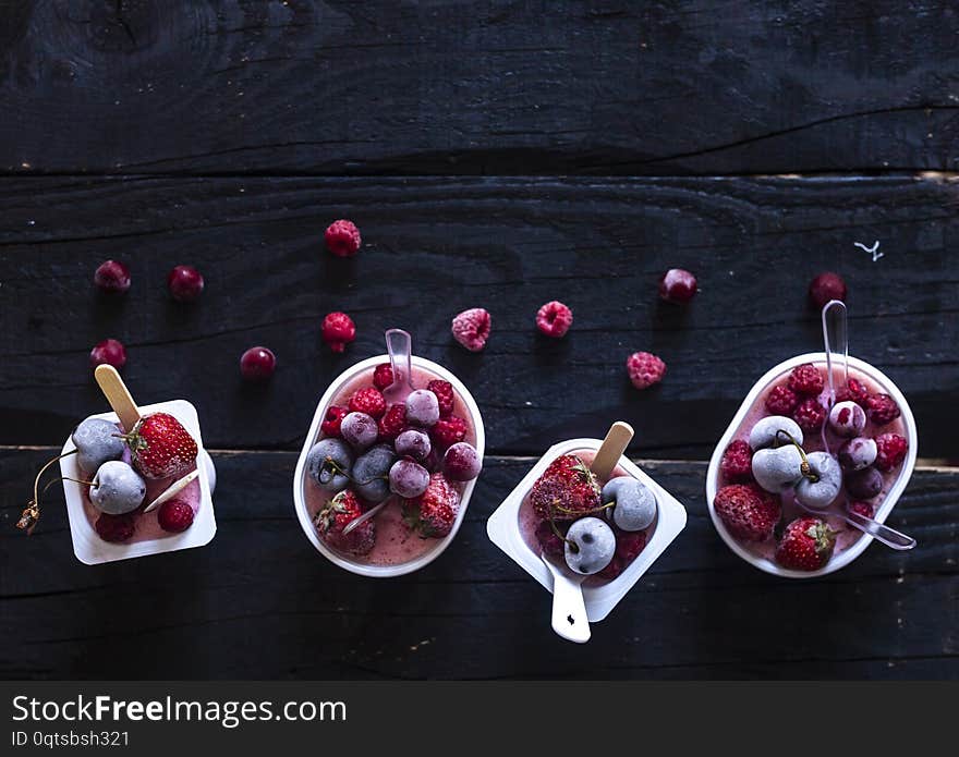 Homemade fresh yogurt. Healthy sweet dessert on dark rustic wood. Frozen fruits