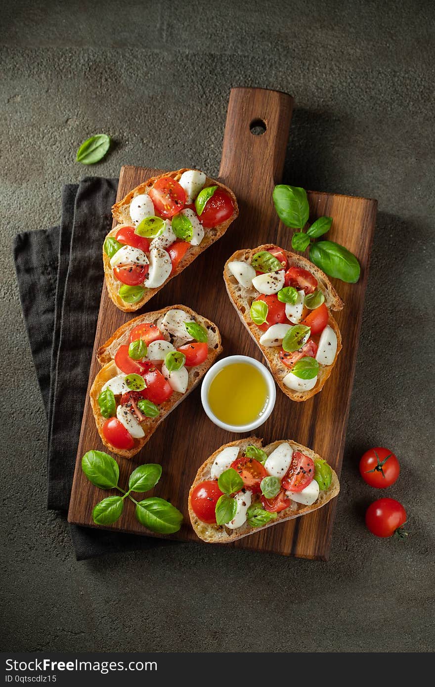 Bruschetta with tomatoes, mozzarella cheese and basil on a cutting board. Traditional italian appetizer or snack, antipasto. Top view. Flat lay.