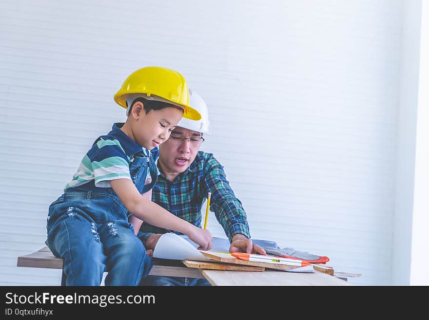 Builder Father is teaching his son to read the construction plan paper