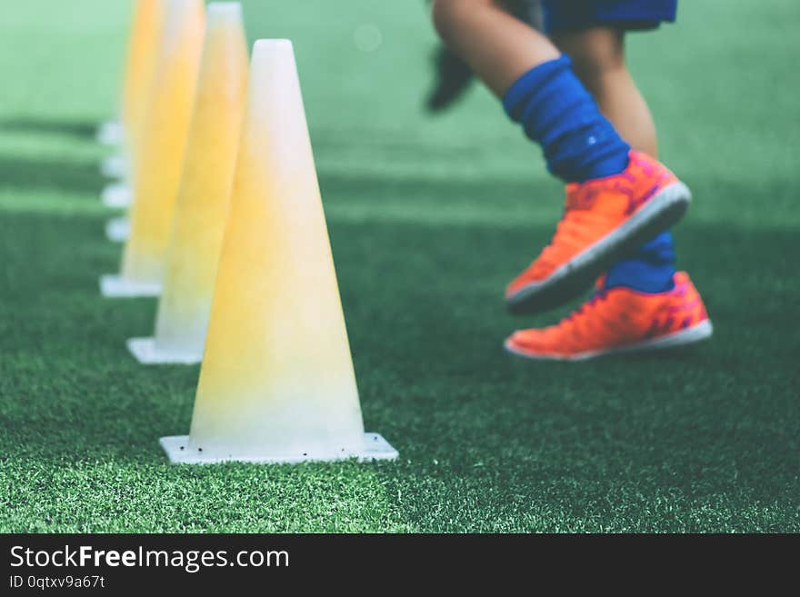 Feet with soccer boots training on training cone on soccer ground