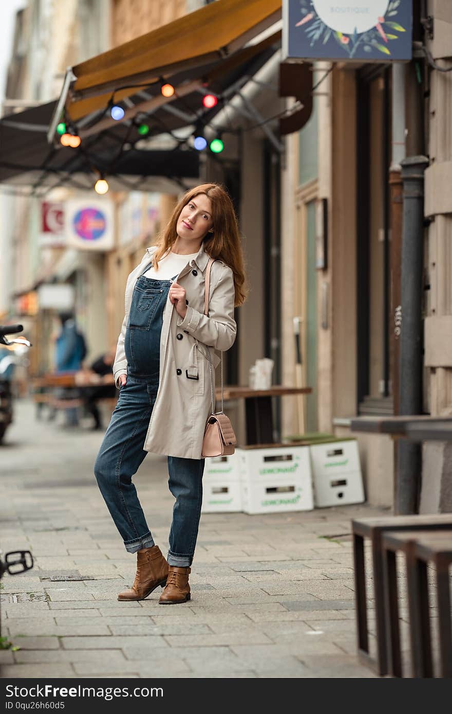 Beautiful young pregnant woman wearing casual clothes walking through the city streets. concept of motherhood and pregnancy.