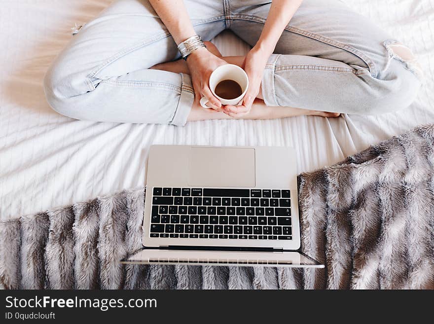 Unrecognized woman drinking coffee and watching a Tv series on her laptop