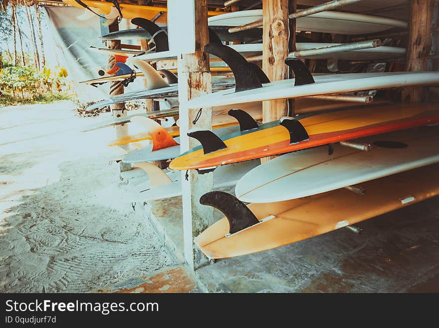 Different colorful surf boards in a stack available for rent on the beach