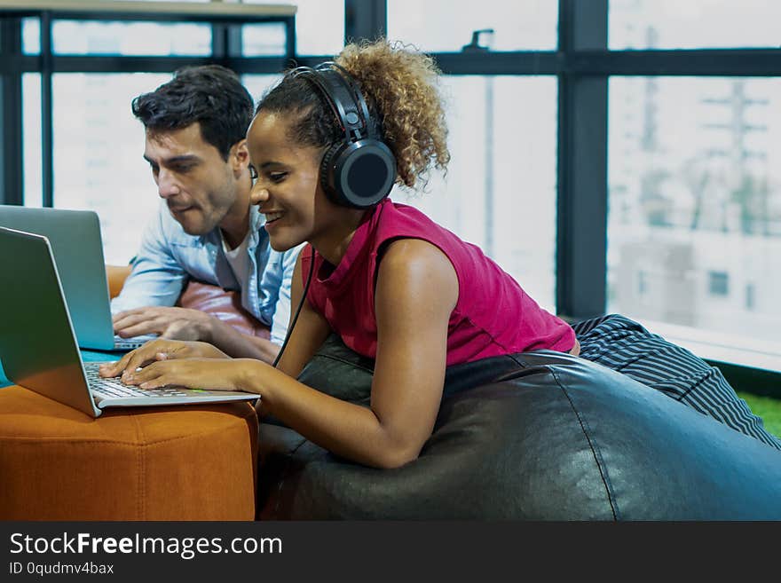 Office couple working together using laptop computer and working woman listen to music with headphone