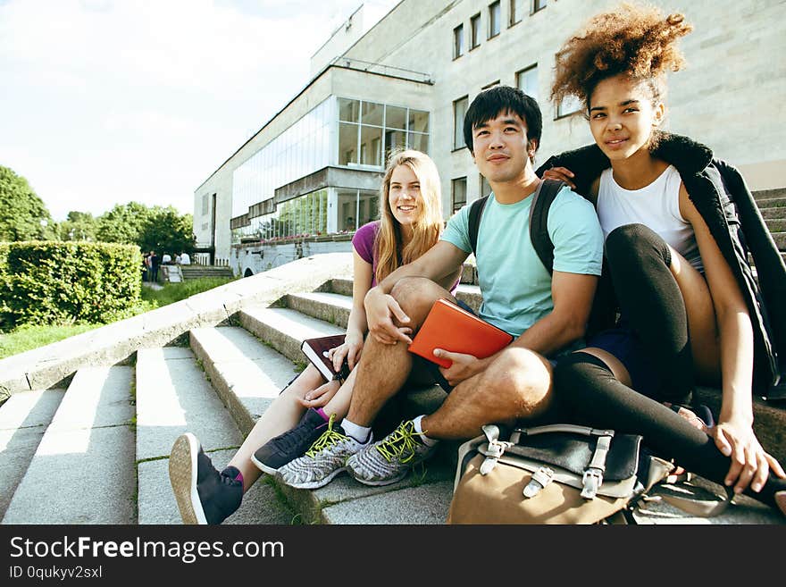 Cute group of teenages at the building of university with books huggings, diversity nations real students lifestyle