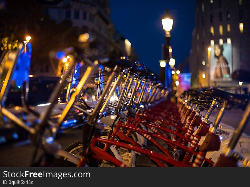 Red parked rental bikes at night perspective shot from Barcelona