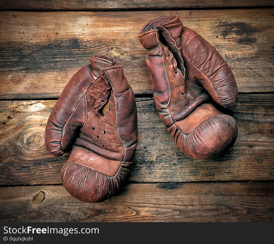 very old leather brown boxing gloves on a shabby wooden board