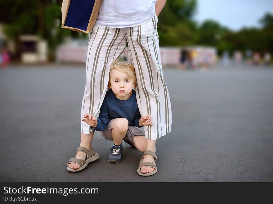 Little playful boy having fun during walking with his mother. Child fooling around warm summer evening in public park. Hyperactive kid