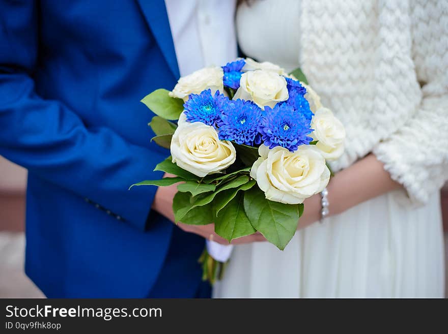 Beautiful wedding bouquet of blue and white roses in the hands of the bride and groom close-up. Beautiful wedding bouquet of blue and white roses in the hands of the bride and groom close-up