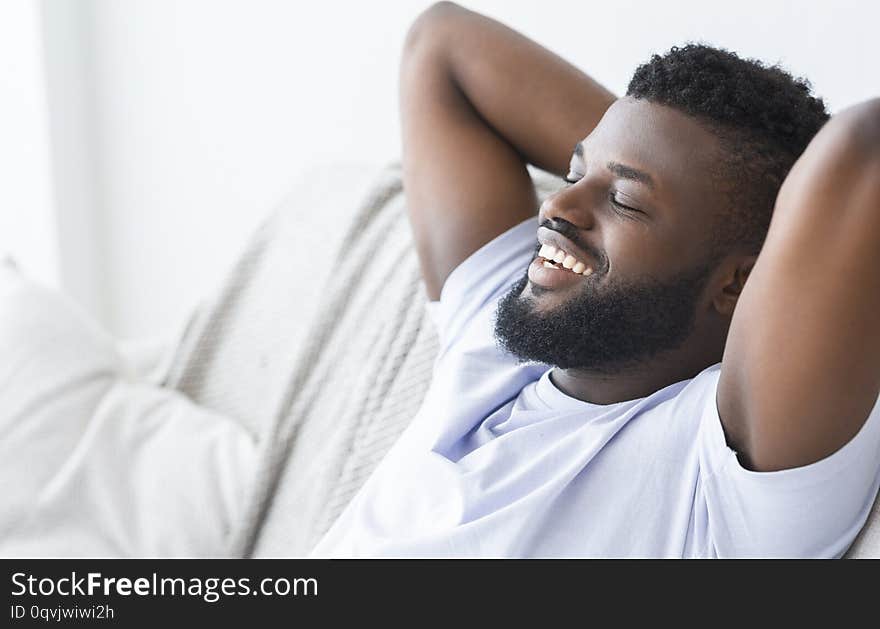 Free time. Happy african man enjoying weekend, relaxing at home, empty space