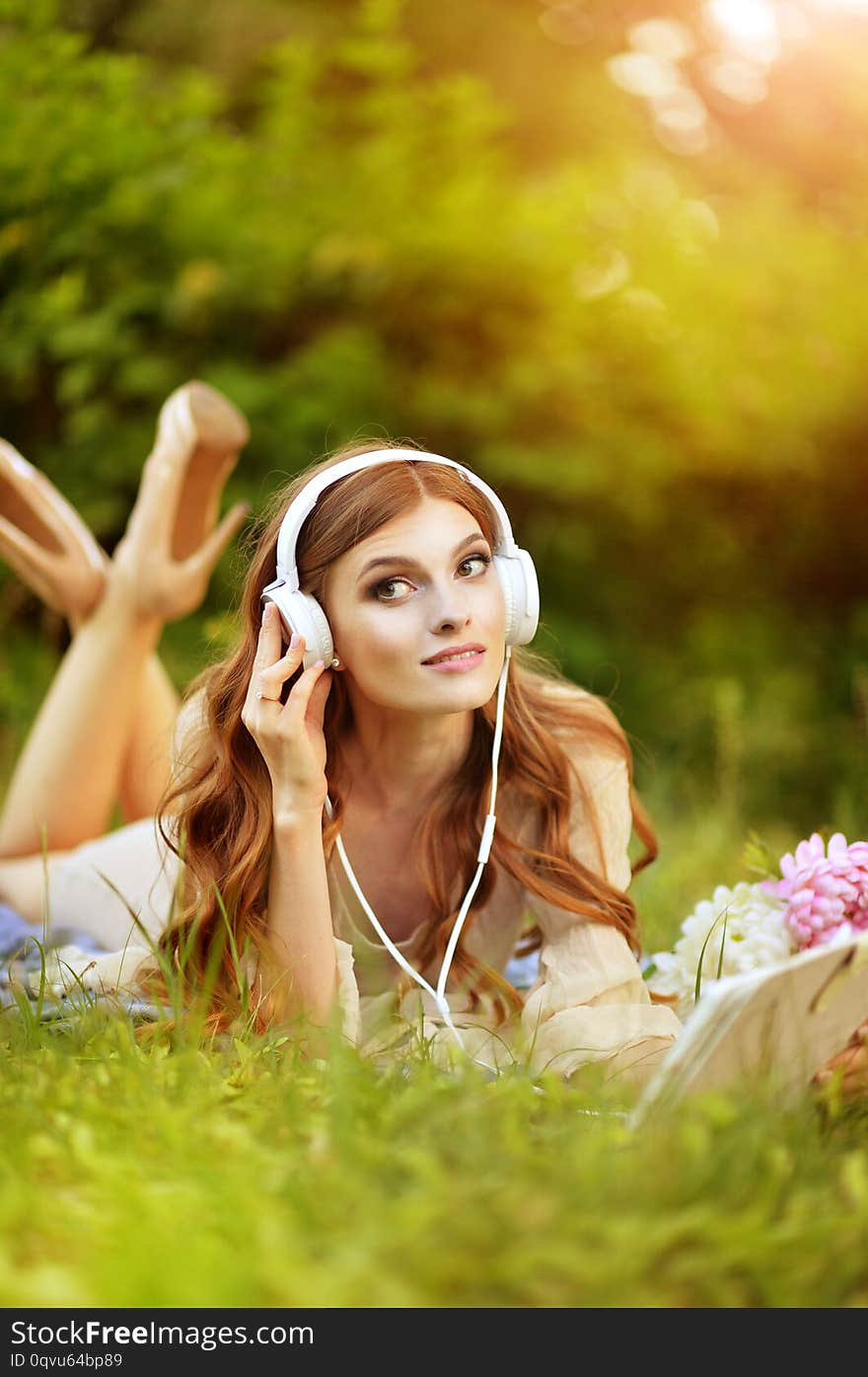 Beautiful young woman lying on green meadow and listening music from tablet. Beautiful young woman lying on green meadow and listening music from tablet