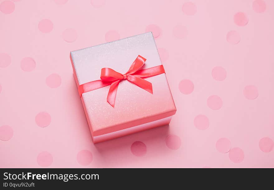 Pink present box on pink konfetti background. Top view, flat lay. Holiday gift concept