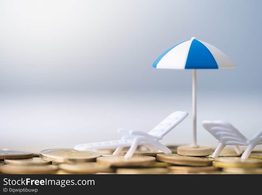 Umbrella and chair on coins stack. Summer vacation concept. travel and money concept. Concept summer holiday adventure trip. high season