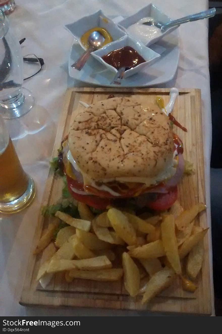 HAMBURGER ON WOODEN TABLE WITH FRIED POTATOES AND SAUCES OF VARIOUS COLORS AND FLAVORS IS A FAST OR CHATARRA FOOD