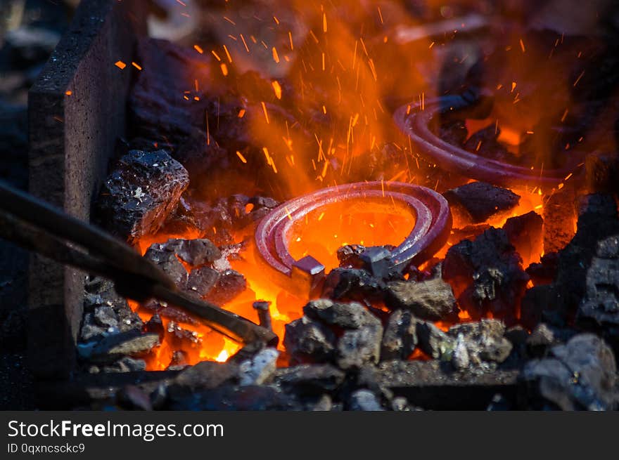 blacksmith furnace with burning coals, tools, and glowing hot horseshoe, close-up