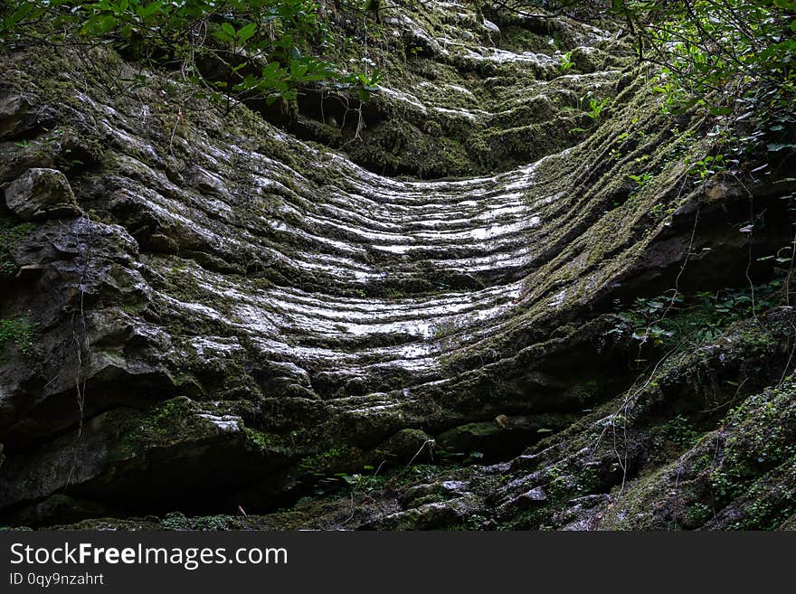 Rock of layered stone overgrown with grass and moss