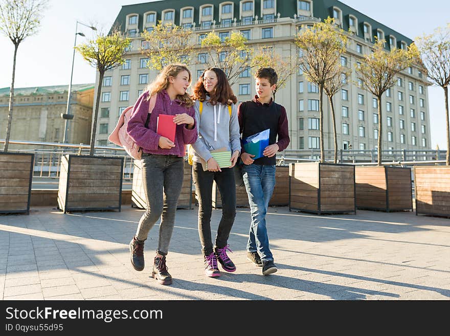 Outdoor portrait of teenage students with backpacks walking and talking