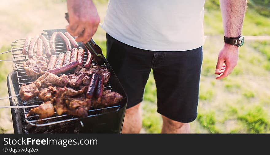 Grilling sausages on barbecue grill.