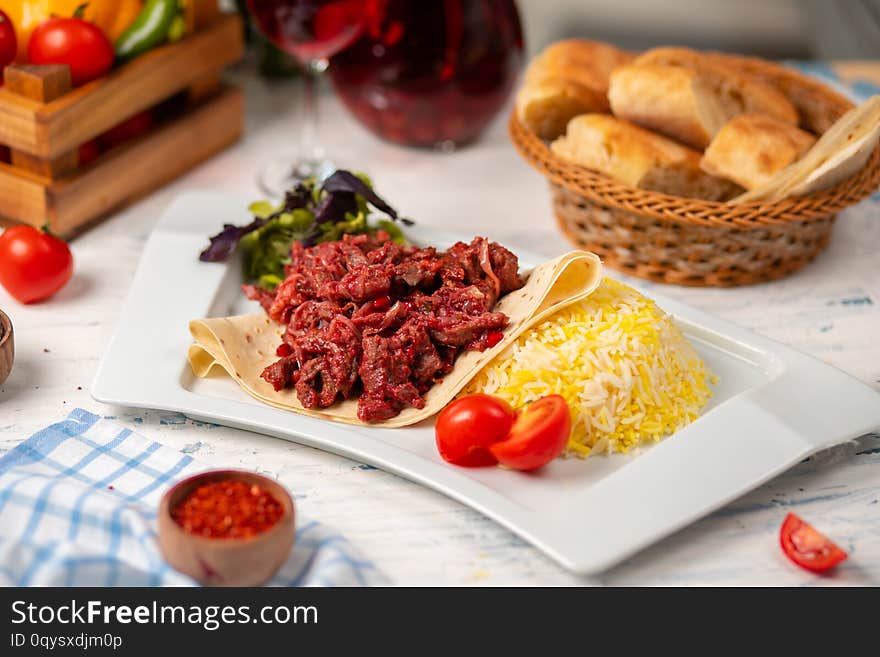 Grilled bbq beef meat slices, doner in lavash with green salad, tomatoes and rice garnish.