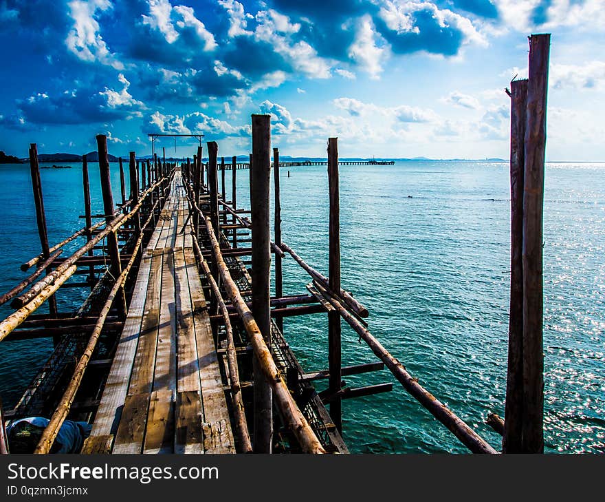 A wooden bridge with a path to the sea, the day when the sky is blue, the sky is bright, the blue sea is a wooden boat dock of olden days