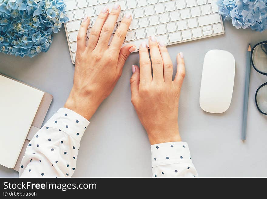 Op view of hands in a polka-dot shirt typing on a computer keyboard