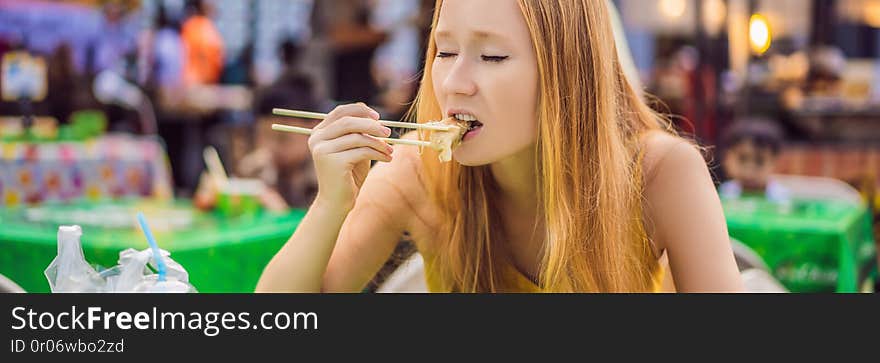 Happy cute gilr eating street food and looking enjoyable in a traditional small fair BANNER, LONG FORMAT