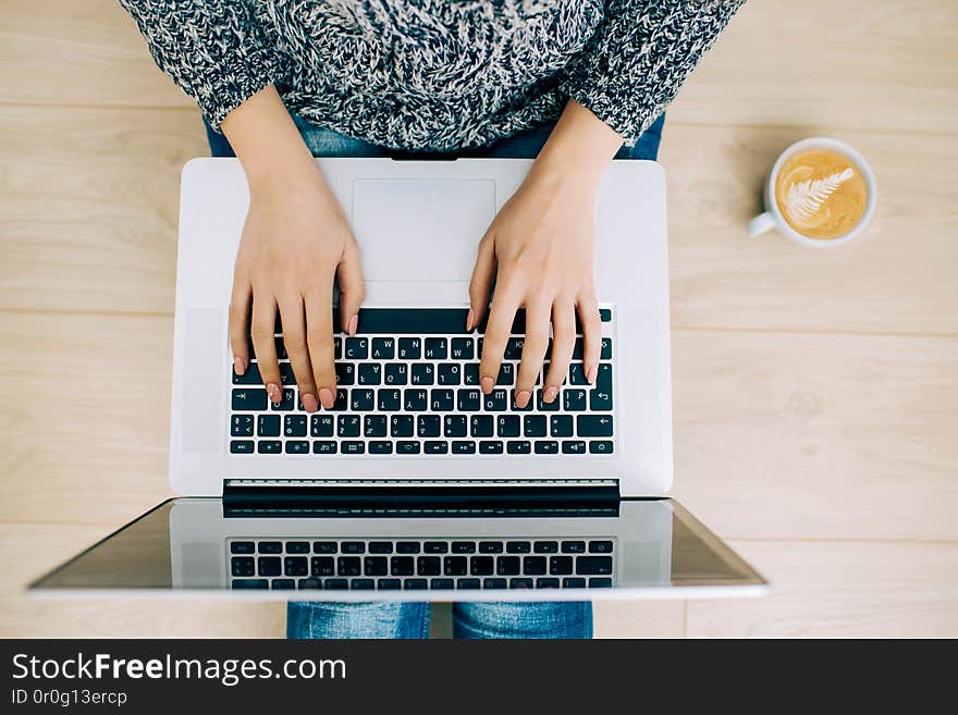 Woman freelancer working on a laptop from home. Flatlay with hands and coffee mug. Woman freelancer working on a laptop from home. Flatlay with hands and coffee mug.